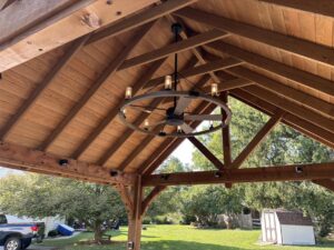 This pergola hangs over an outdoor kitchen and includes a fan, lighting, and electricity.