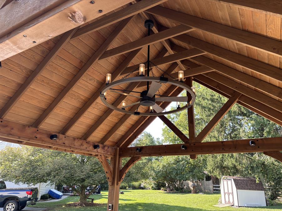 This pergola hangs over an outdoor kitchen and includes a fan, lighting, and electricity.